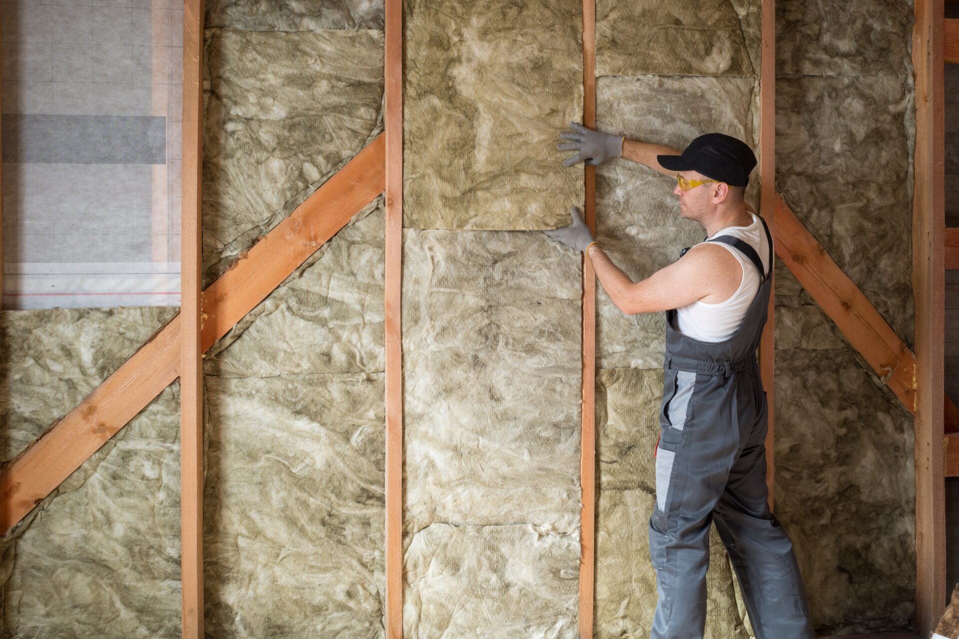 A,Construction,Worker,Insulates,The,Wall,Of,A,Frame,House